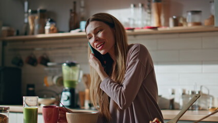Domestic woman talking cellphone at kitchen close up. Smiling girl calling home