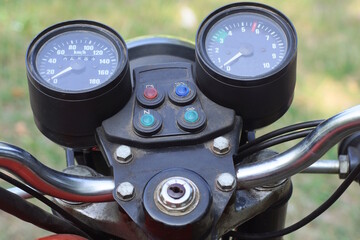 Fototapeta premium two black round plastic speedometers on the dashboard of an old motorcycle on a summer street