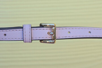 metal clasp on long thin leather pink bag strap on yellow background