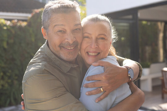 Hugging and smiling, senior diverse friends enjoying time together outdoors, at home