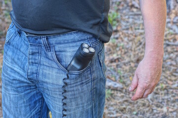 one black electric razor with a cord lies in the pocket of blue jeans on a man on a summer street