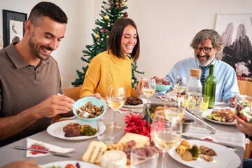 Laughing European diverse happy family having fun celebrating Christmas at home gathered sitting festive food table with roast turkey eating meal and enjoying in winter merry vacation together indoors