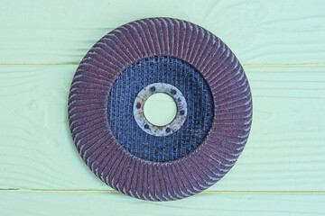 one old round brown black grinding wheel lies on a yellow wooden table