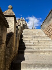 Fototapeta premium Alcázar of Segovia Turret Walkway – Historic stone walkway with castle turret and dramatic shadows under blue skies atop the iconic medieval fortress in Segovia, Spain
