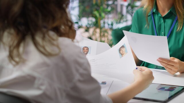 Human resources staff evaluating candidates resume in the selection process, reviewing all applicants after job interview in order to hire the right person. Recruiters seeking personnel. Camera A.