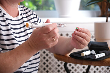 middle aged woman preparing syringe pen with insulin for injection, diabetes concept, diabetes...