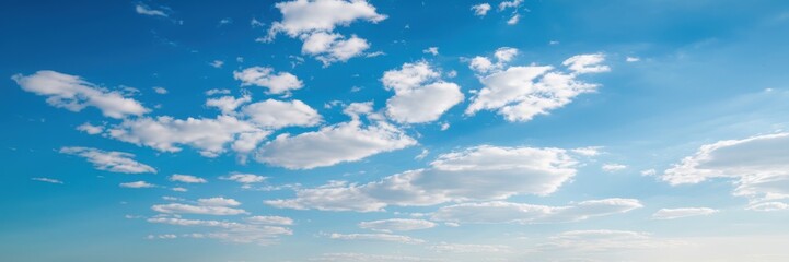 Obraz premium A serene view of a clear blue sky adorned with scattered white clouds on a sunny day.