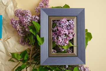 Blue frame mockup with lilac flowers bouquet in beige background, frame mock up with copy space