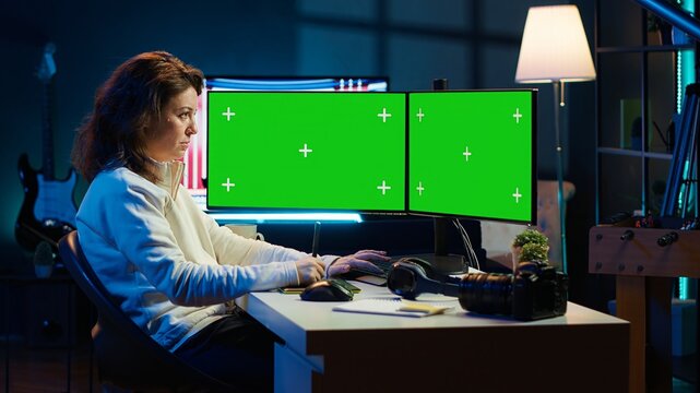 Photographer using photo editing software on chroma key multi monitors setup to improve images quality. Photo editor utilizing pictures retouching application on green screen display, camera A
