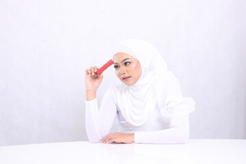 beauty makeup lips adult woman asia hijab beautiful elegant see lipstick hand clamp sideways lipstick container stick forehead isolated white background. cosmetic advertising,lip balm,lipstick mock up