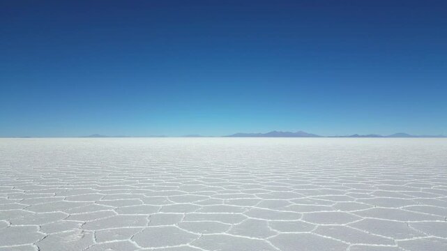 Drone shot flying low and straight over the Salar de Uyuni in Bolivia, Bolivia, the world's largest salt flat, towards the mountains on the horizon