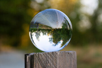 A image of a photographic lens tool resting on a wooden fence post and reflecting an inverted image...