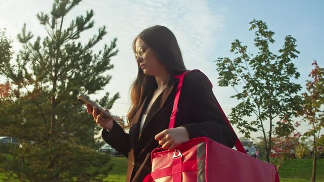 Charming young courier takes a moment to survey the urban scenery and locate the destination for her delivery.