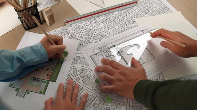 Smart architect and safety engineer discussion about building blueprint on table with architectural document, measurement tools and wooden block scatter around at modern office. Closeup. Delineation.