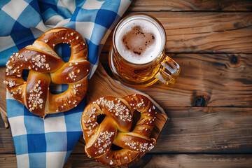 oktoberfest background, a glass of beer and a giant german pretzel on wooden table with blue white checkered flag decoration