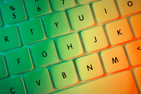 Top view of white computer keyboard illuminated with colorful lights, close-up shot