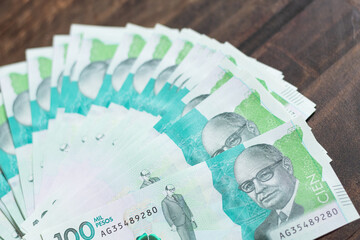 Banknotes of 100,000 Colombian pesos spread out in a fan shape on a wooden table. Concept of money,...