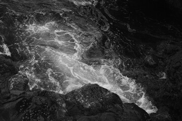 Stormy waves on a rocky seashore. Black and white sea