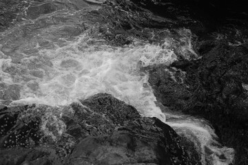 Stormy waves on a rocky seashore. Black and white sea