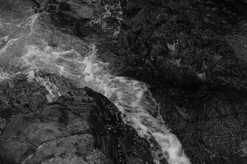 Stormy waves on a rocky seashore. Black and white sea