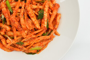 Korean food Seasoned Deodeok mixed with green onion and Kochujang(red pepper paste) in a white dish, South Korea.  Deodeok is Mountain herb whose roots have restorative properties