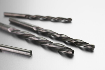 Many different drill bits on light grey background, closeup