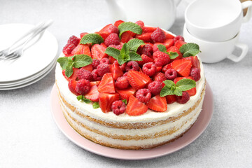 Tasty sponge cake with fresh berries and mint on light gray table