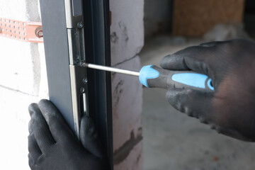 Repairman installing new door with screwdriver indoors, closeup