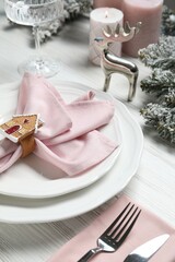 Plates, napkin, cutlery, glass and Christmas decor on wooden table, closeup