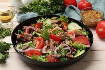 Delicious fresh tuna salad and ingredients on wooden table, closeup