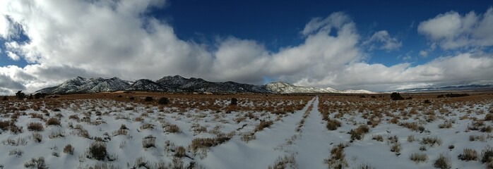 Panoramic winter shot of desert valley with mountains covered in snow