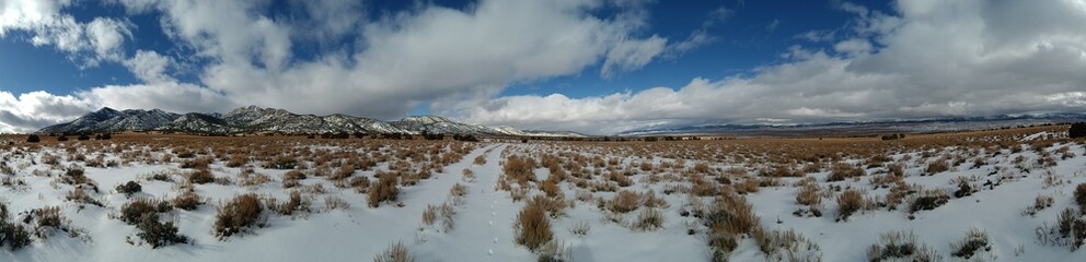Panoramic winter shot of desert valley with mountains covered in snow