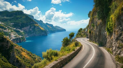 Winding road along a scenic coastline with mountains, sea, and blue sky.