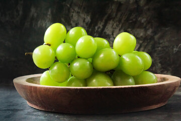 bunch of green grapes in a wooden bowl on a black background