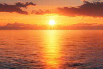 Obraz premium Stunning sunset over calm ocean waters with a vibrant orange and yellow sky.