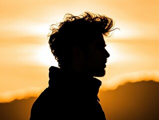 A silhouette of a man against a vibrant sunset, showcasing dramatic lighting and a natural setting that evokes a sense of calm and contemplation.