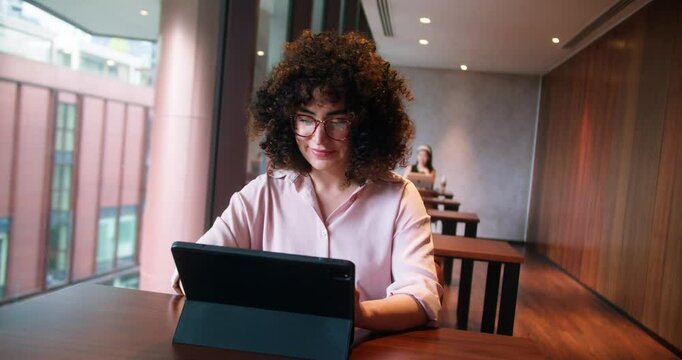 30s mid age European business Caucasian woman CEO using laptop for work sitting at table in office and looking at camera. Smiling mature adult professional businesswoman using pc digital computer