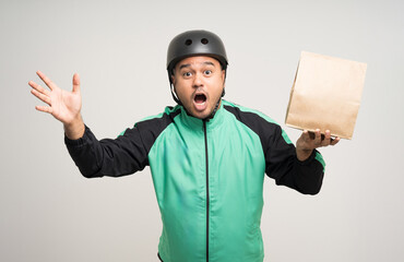Young asian rider wearing green jacket uniform and bike helmet various action holding food paper bag delivery to customer. Male delivery service worker. Courier and shipping food service.
