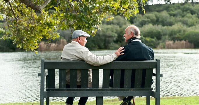 Park, bench and senior friends by lake for retirement with conversation for bonding together outdoor. Calm, nature and elderly men relaxing and talking by water in assisted living garden in winter