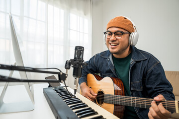 Professional Musician with condenser microphone and tablet for Mixing Mastering music. Music composer male composing a song with guitar and piano keyboard at digital Recording home studio