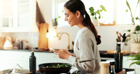 Phone, cooking and woman in kitchen with smile, healthy food and online recipe for lunch. Diet, nutrition and happy girl with smartphone, research and website for dinner meal prep advice in home