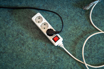 three-socket power strip on a dirty floor, highlighting the contrast between technology and...