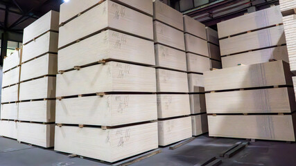 A stack of wood planks are piled high in a warehouse