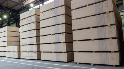 A large stack of wood is piled high in a warehouse