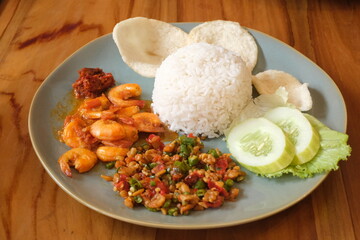 a plate of food with rice, shrimp, cucumber and crackers.