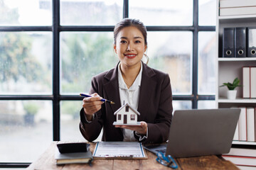 Guarantee, Mortgage, agreement, contract, Signing,asian woman work at desk reading agreement document to sign land loan with real estate agent or bank officer, insurance concepts.
