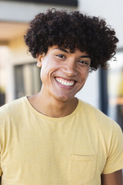 Smiling young man in yellow shirt enjoying time with diverse friends outdoors, at home
