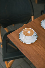 A cup of aromatic cappuccino on wooden table on the cafe's terrace