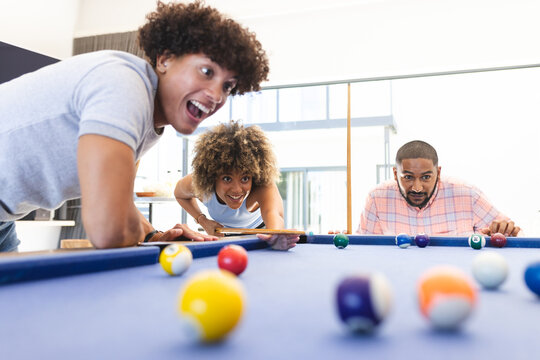 Playing pool, diverse friends enjoying fun and competitive game together indoors, at home