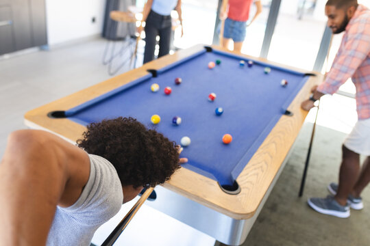 Playing pool, diverse friends enjoying game of billiards in casual setting, at home
